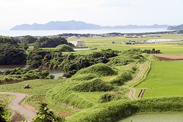 中央に丸く盛り上がった古墳がある新原・奴山古墳群の写真