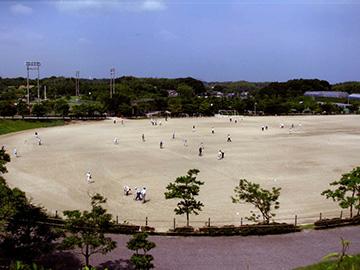 広場でまばらに人が散らばっていて、野球をしている写真