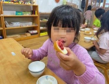 いちごジャムパンを美味しそうに食べる園児