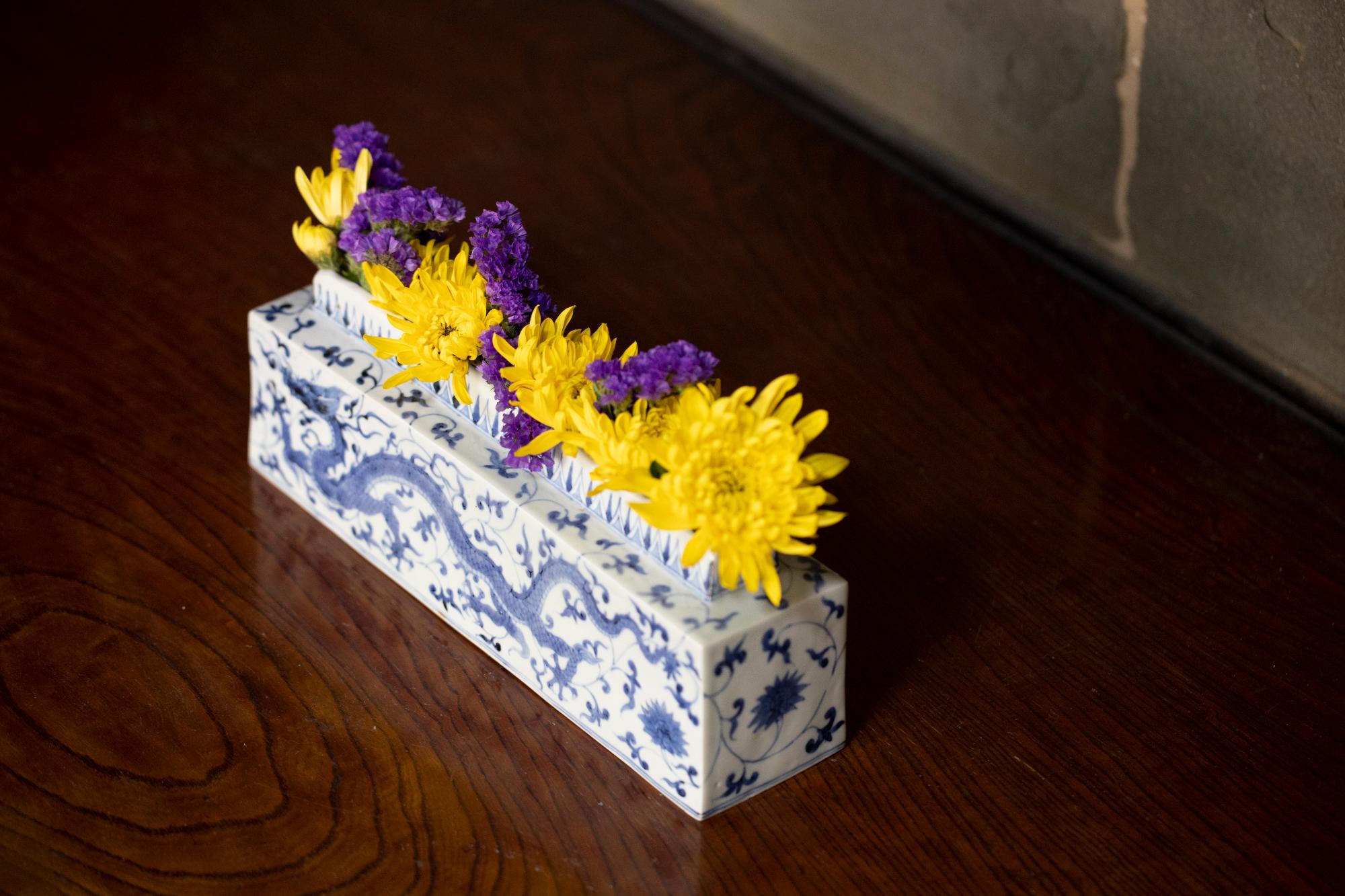 龍の文様が描かれた花器に黄色と紫の花がいけてある