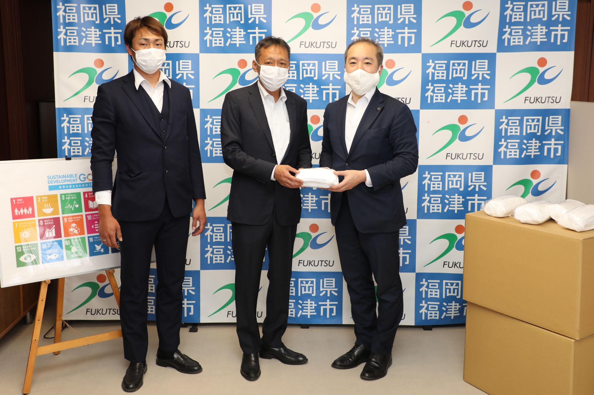 原崎市長にマスクを手渡しするNPO法人環境・人アシストの廣嶋さん