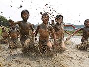 子どもたちが上半身裸で泥の中で遊んでいる写真