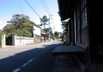 道路沿いに建っている古民家の入り口にあるベンチの写真