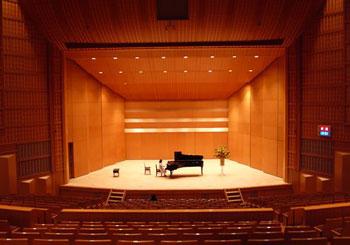 カメリアホールの舞台の中央におかれたグランドピアノを女性が弾いている写真