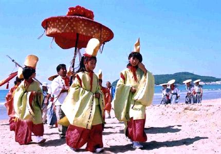 宮地嶽神社秋祭りで、宮地浜を黄色と赤の袴の衣装を着た女の子たちが歩いている写真