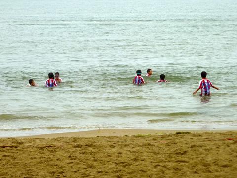 男児たちがサッカーのユニフォームのままで海に入っている写真