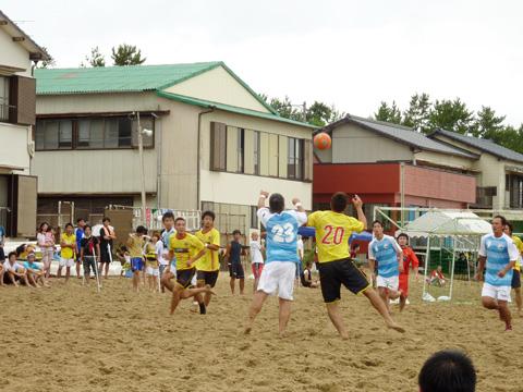 男性たちによるビーチサッカーの試合で蹴られたボールが上に上がりそのボールを競って取ろうとしてる写真