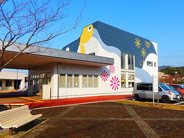 白い壁に黄色やピンクで花火のようなイラストが描いてある児童センターの外観の写真