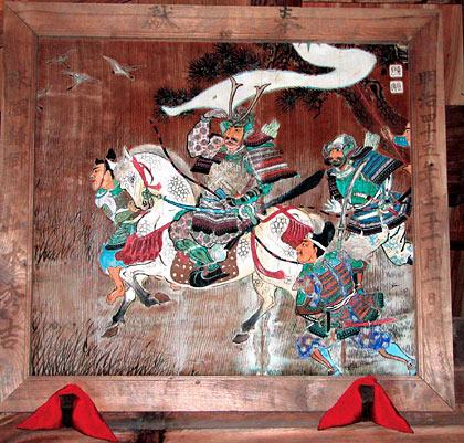 鎧兜を被った武士が白い馬に乗っていて、馬の周りを家来たちが走っている姿が描かれている雁行乱知伏兵図の写真