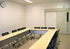 長机が長方形の形になるように置かれていて、その周りに椅子が置かれた会議室の写真