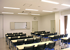 長机が横2列、縦に5列で置かれていて、前方にはホワイトボードがある研修室の写真
