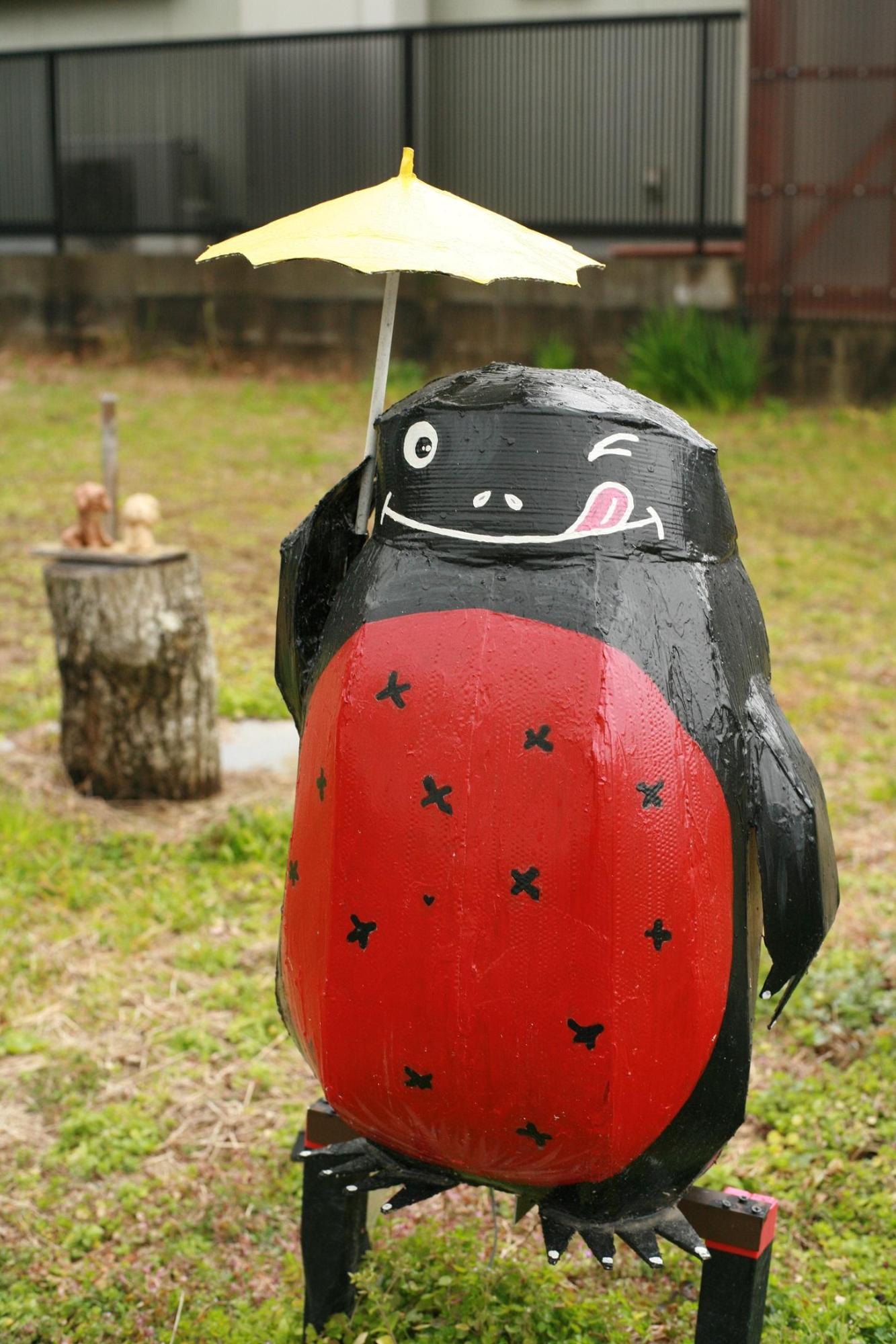 赤いお腹と黒い体のアカハライモリが傘をさしている置物の写真