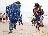 砂浜で大人が2人獅子舞の格好をしている姿を人が見ている写真