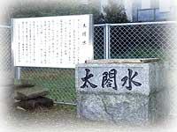 「太閤水」と大きな太文字で書かれた石ずくりの井戸があり、その隣に掲示板が置いてある写真