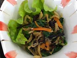 サラダ菜の敷いてある器に切干大根、ひじき、にんじん、小松菜の入った煮物が盛り付けられている写真