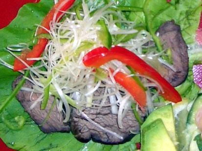 サラダ菜の上にローストビーフ、白髪葱と赤ピーマンがトッピングされた写真